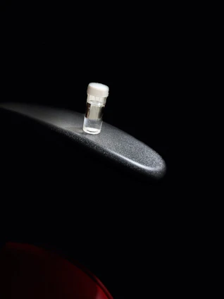 Close-up of a vial filled with clear peptide solution resting on a wooden table with soft natural light.