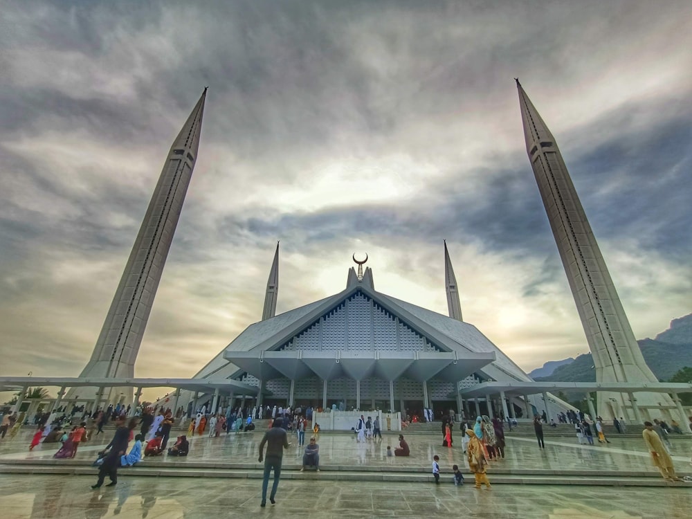 a large building with a glass front with Faisal Mosque in the background