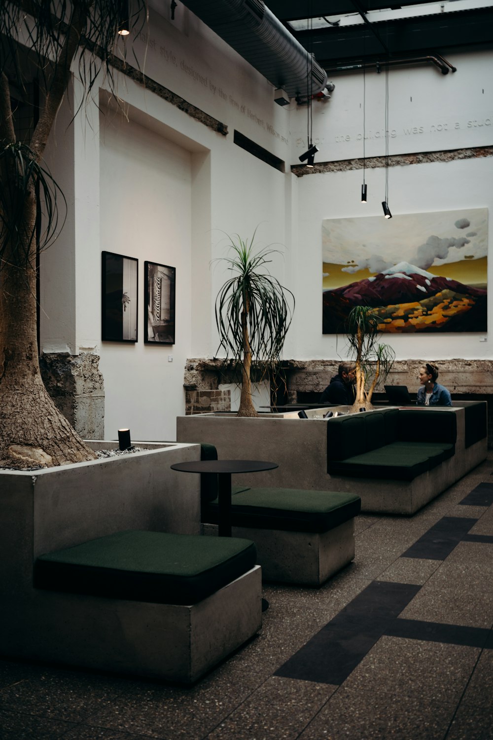 a group of people sitting on a bench in a room with art on the wall