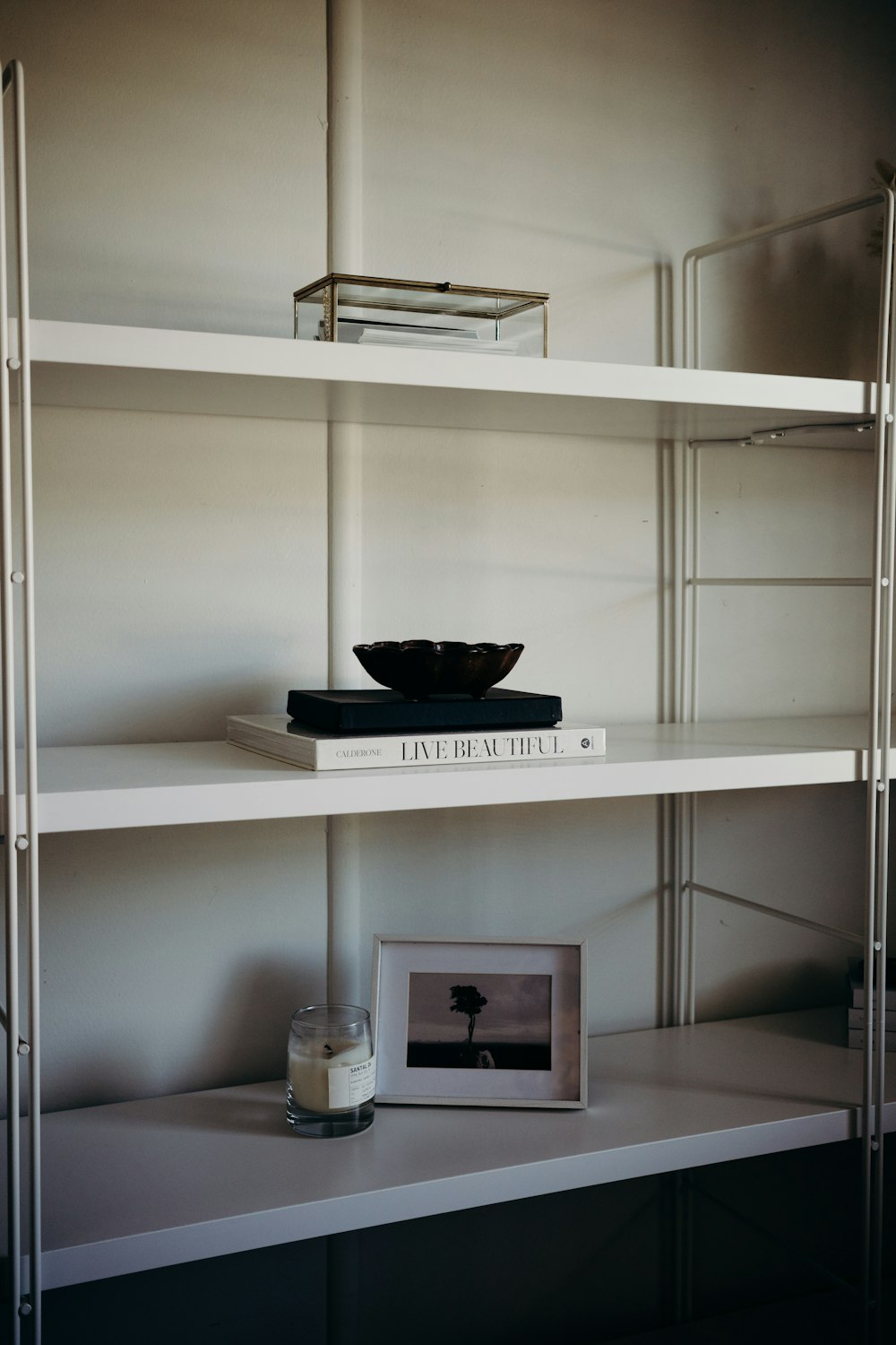 a shelf with a picture and a bowl on it