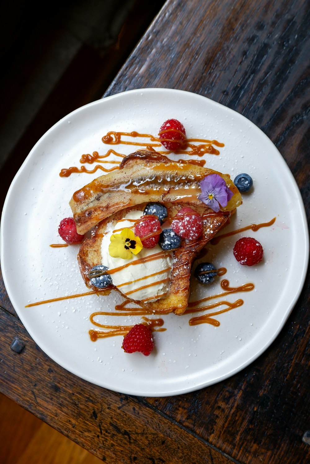 a plate of waffles with fruit and syrup