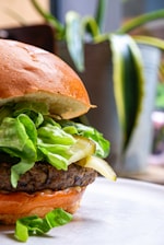 A close-up of a seaweed burger with smoky BBQ sauce, fresh lettuce, and a toasted bun.