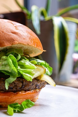 A close-up of a seaweed burger with smoky BBQ sauce, fresh lettuce, and a toasted bun.