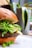 Close-up of a vibrant veggie burger with fresh lettuce, tomato, and a toasted bun on a rustic wooden table.