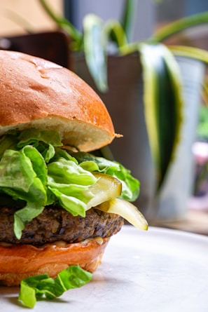 Close-up of a vibrant veggie burger with fresh lettuce, tomato, and a toasted bun on a rustic wooden table.