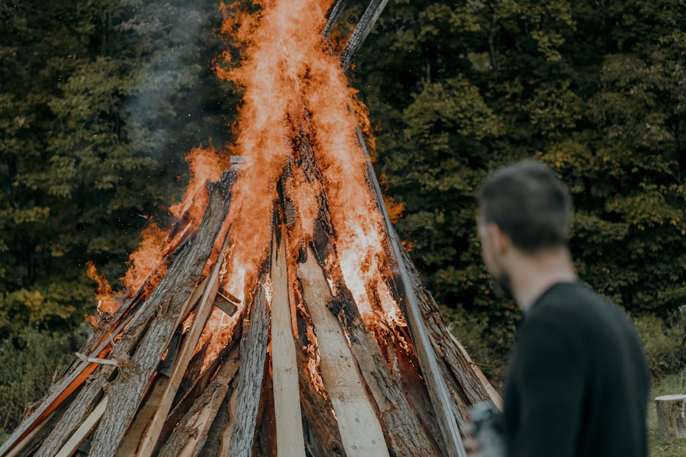 a man standing next to a large bonfire
