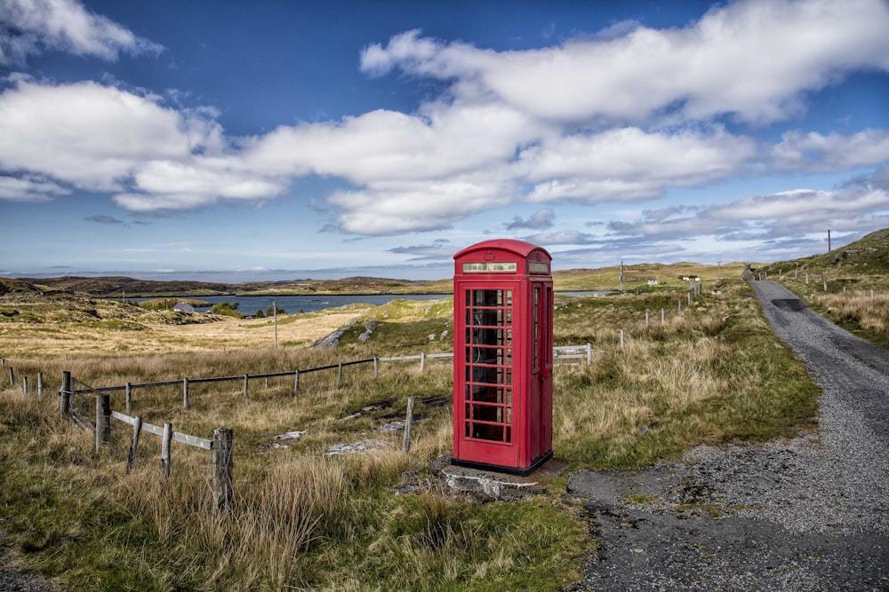 a red telephone booth on a dirt road