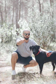 Andre gently guiding a calm dog during a training session in a sunlit forest clearing