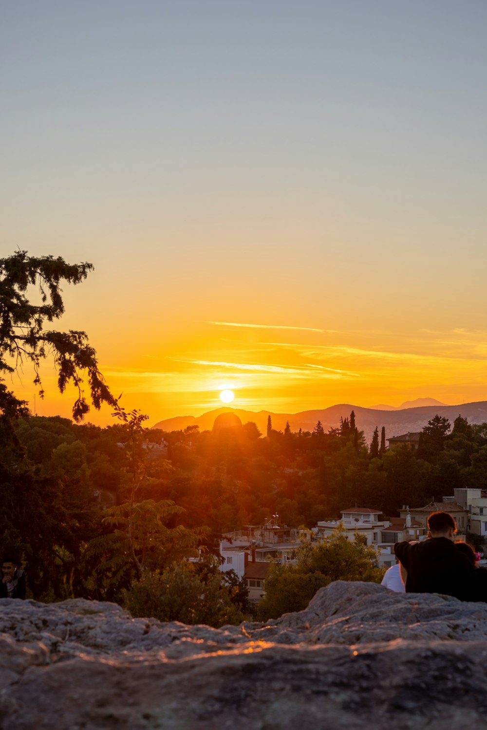 a man sitting on a rock looking at the sunset