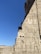 Ancient stone carvings depict figures and hieroglyphics on a wall, set against a clear blue sky. The carvings include detailed representations of human-like figures and intricate symbols.