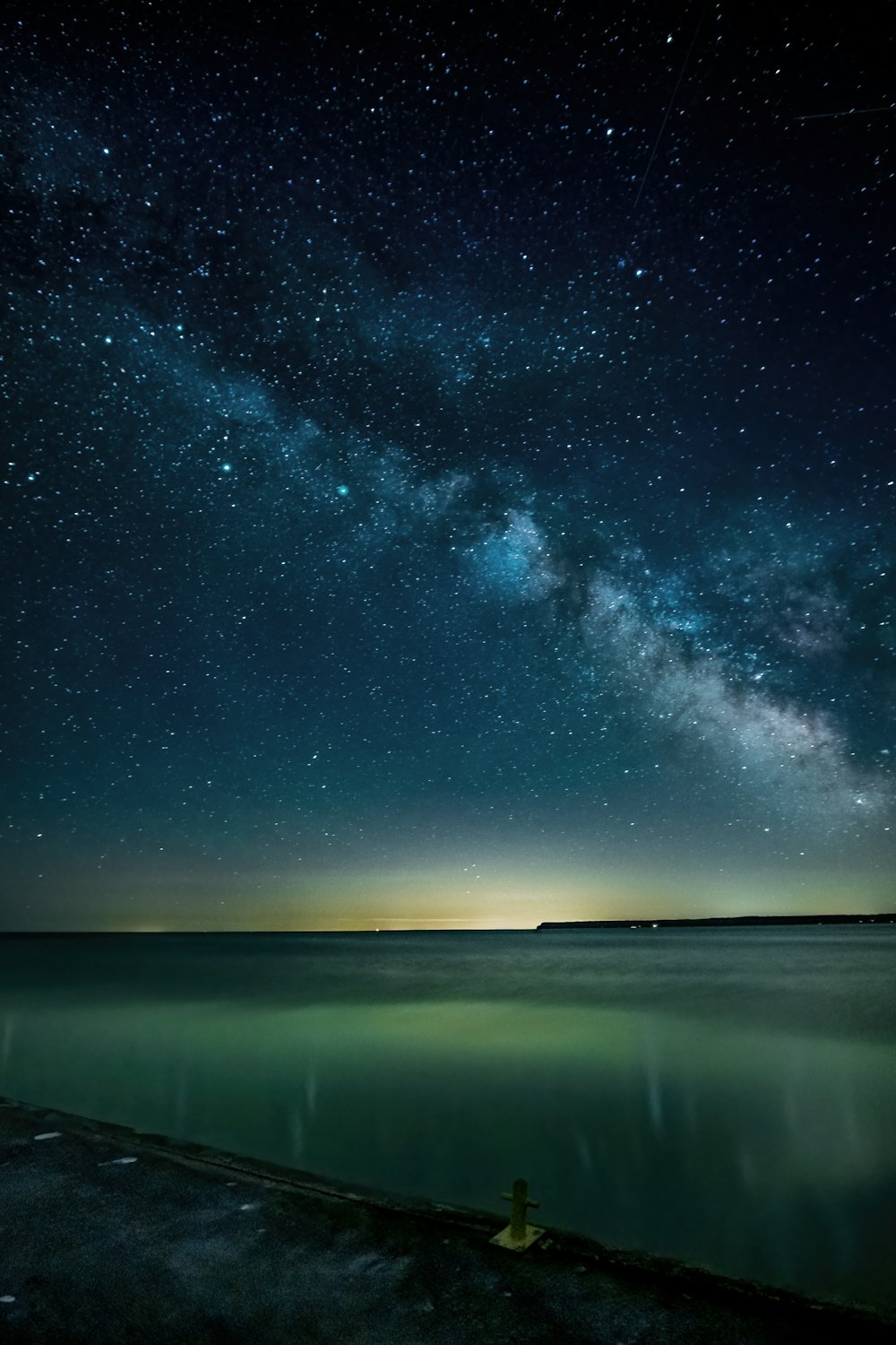 a body of water with a bright light in the sky above it