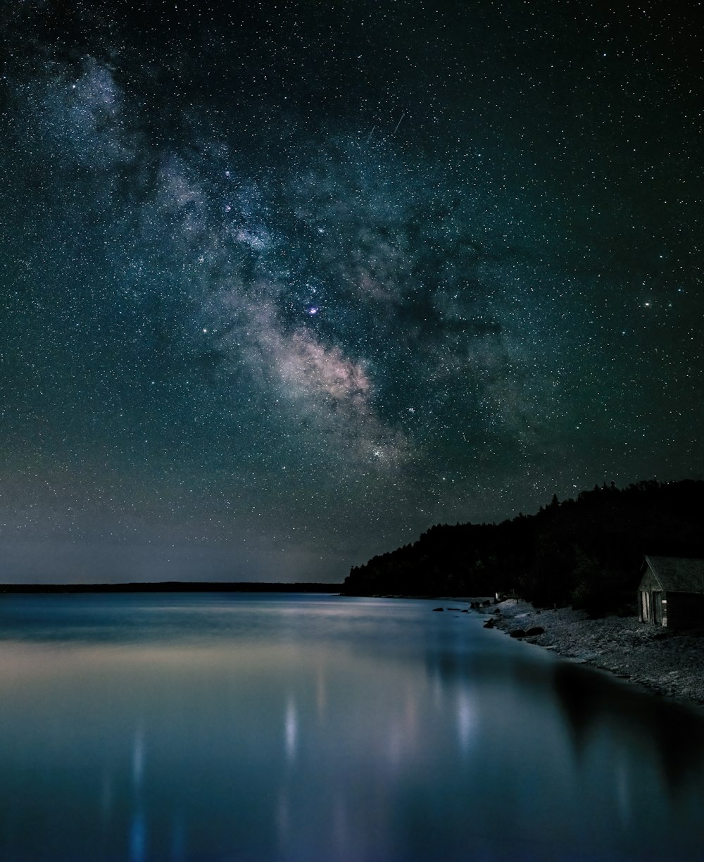 un cuerpo de agua con un cielo estrellado sobre él