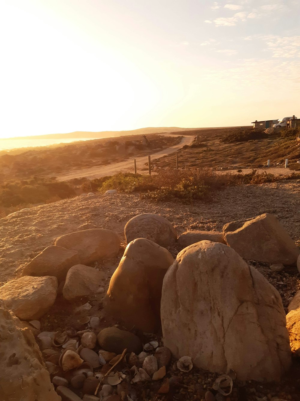 a rocky beach with a fence and a sunset