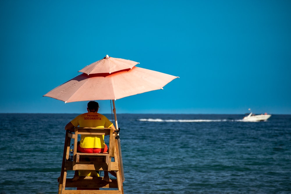a person sitting in a chair under an umbrella on a boat