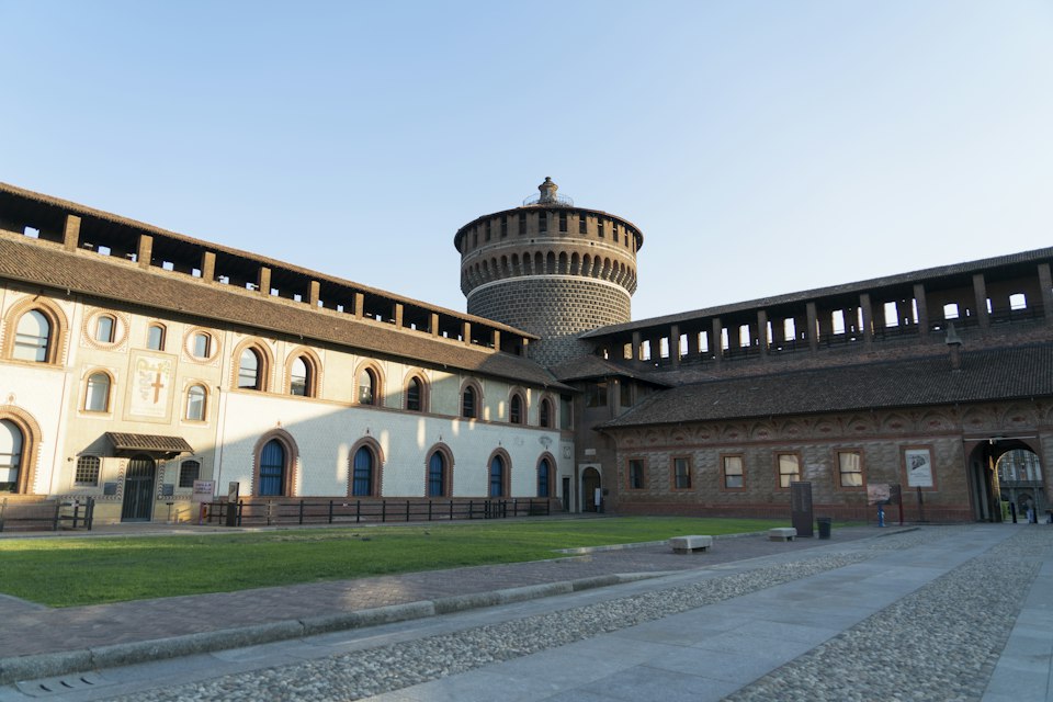 Castello Sforzesco's brick towers rising behind a domed building in Milan