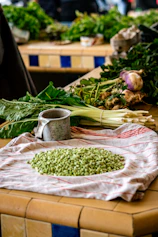 Bundles of fresh green beans and sweet potatoes laid out on a traditional woven mat