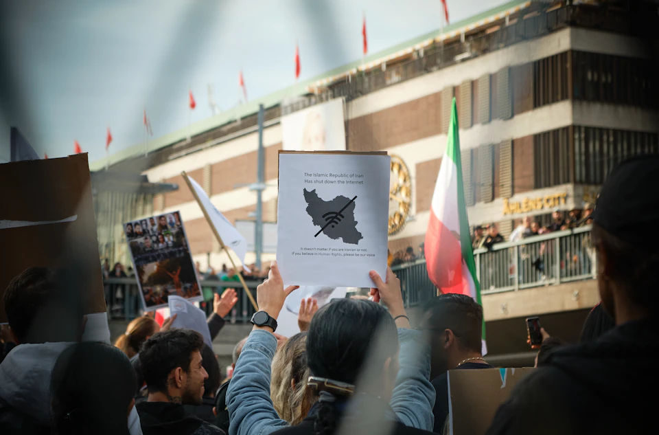 Crowd of protesters holds up signs with various messages, including a banner reading "The European