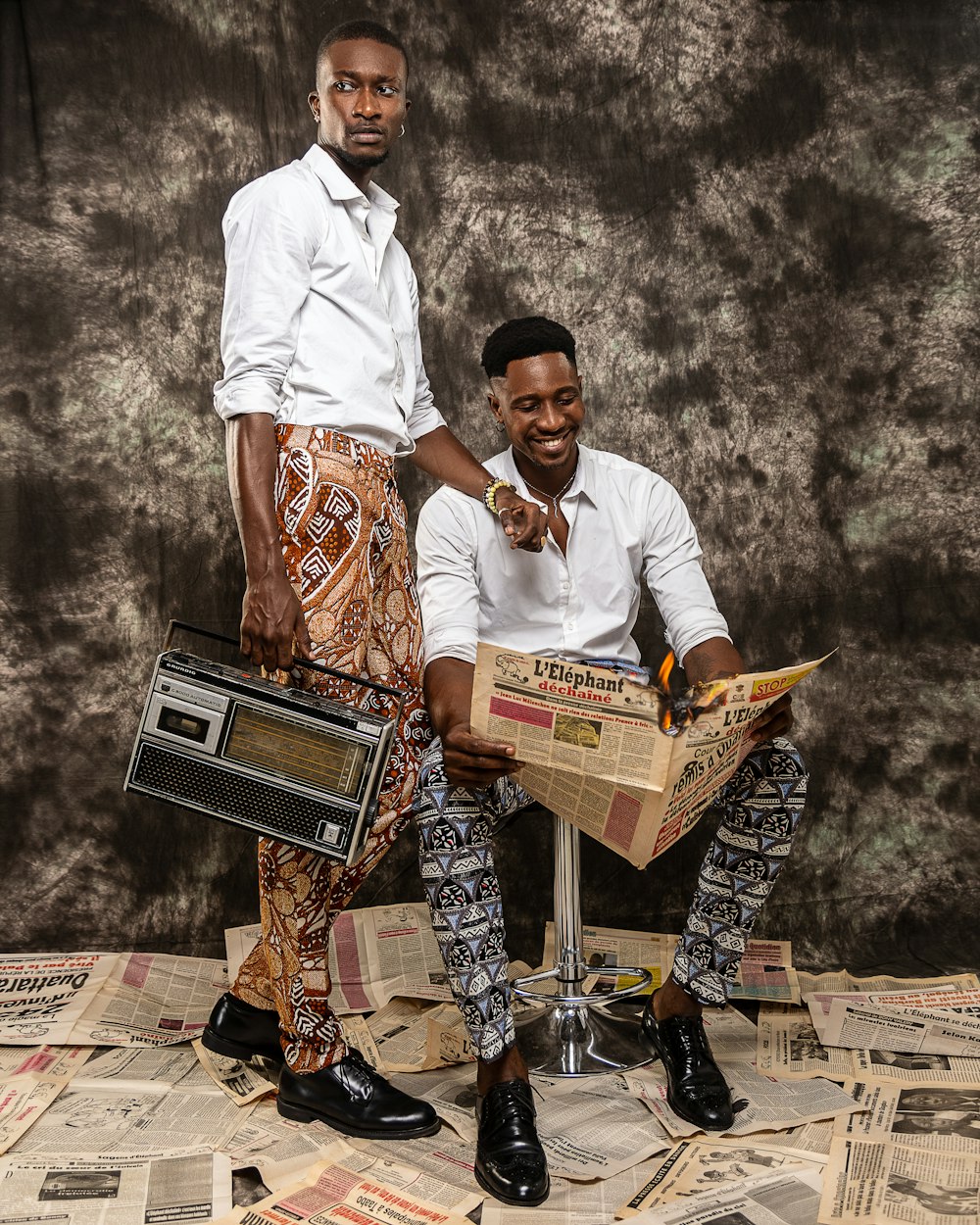 a man holding a box of pizza next to a man holding a pizza