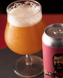 a glass of beer next to a can