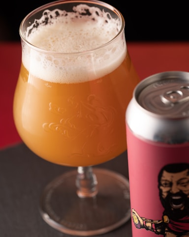 a glass of beer next to a can