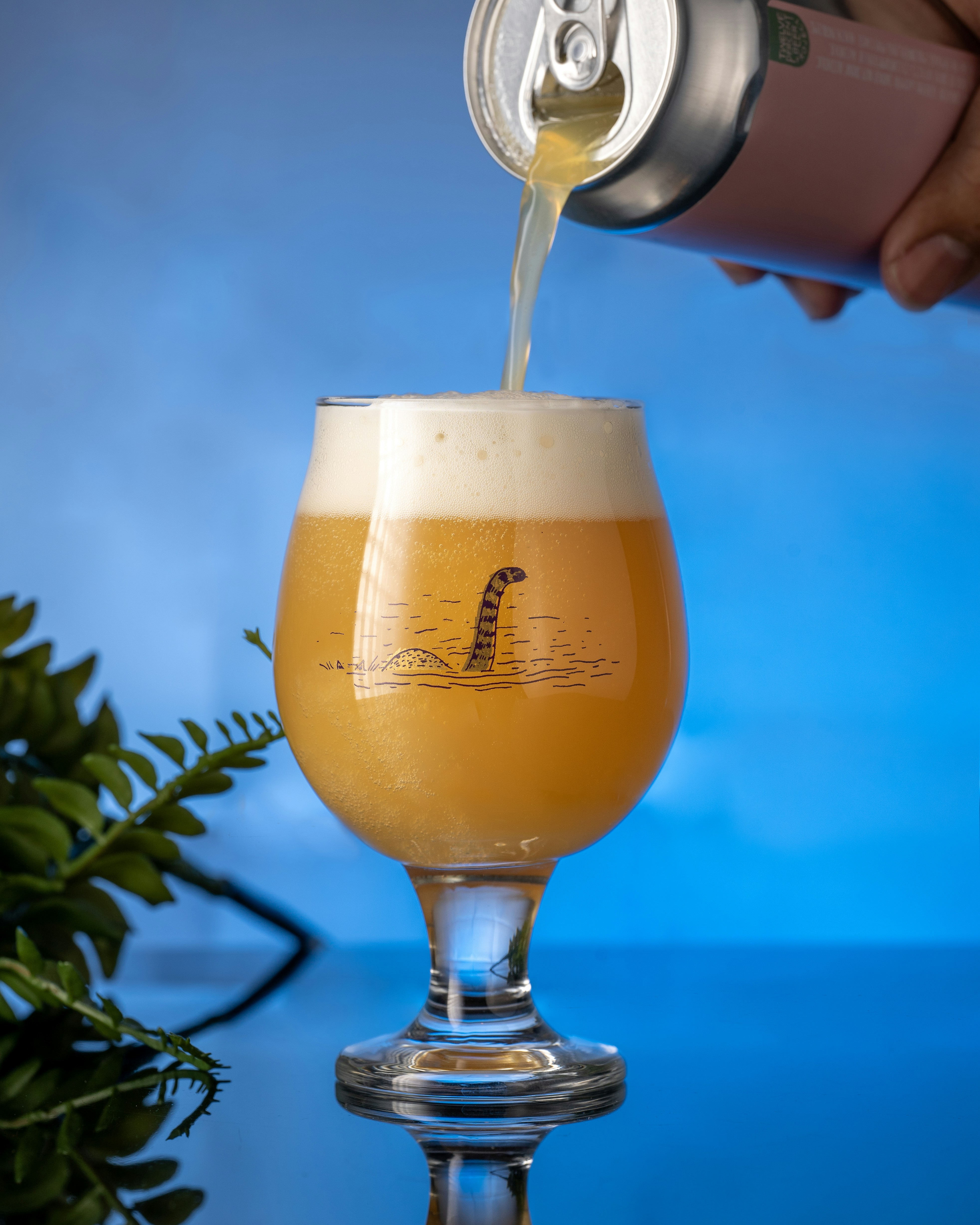 eine Hand schenkt ein Glas Bier ein
