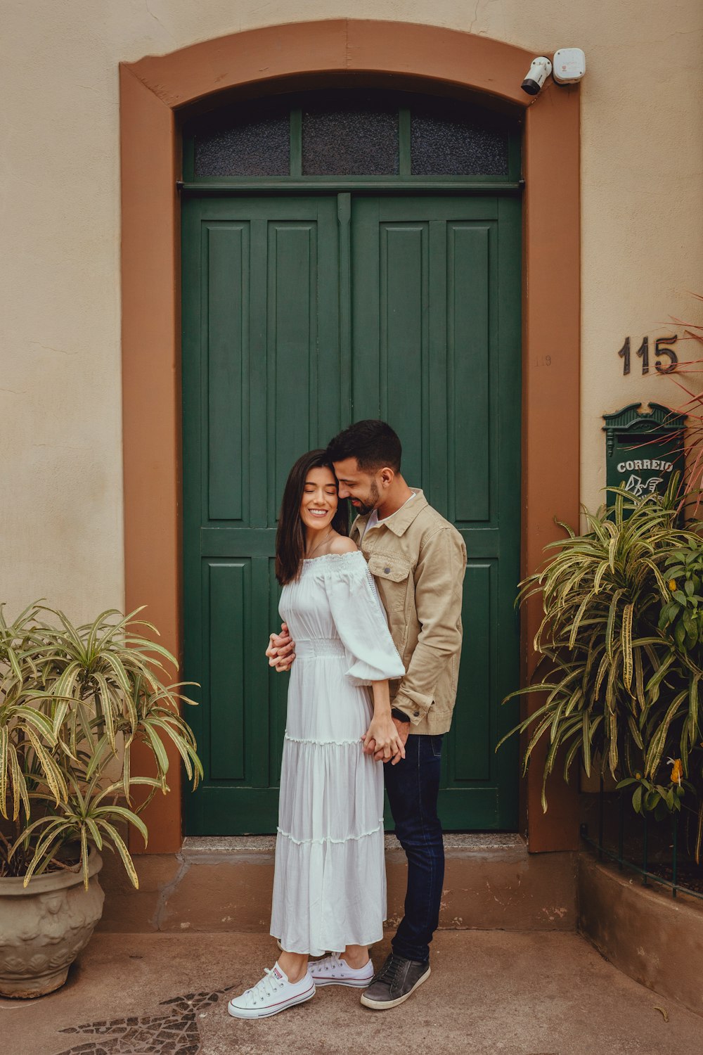 a man and woman kissing in front of a green door