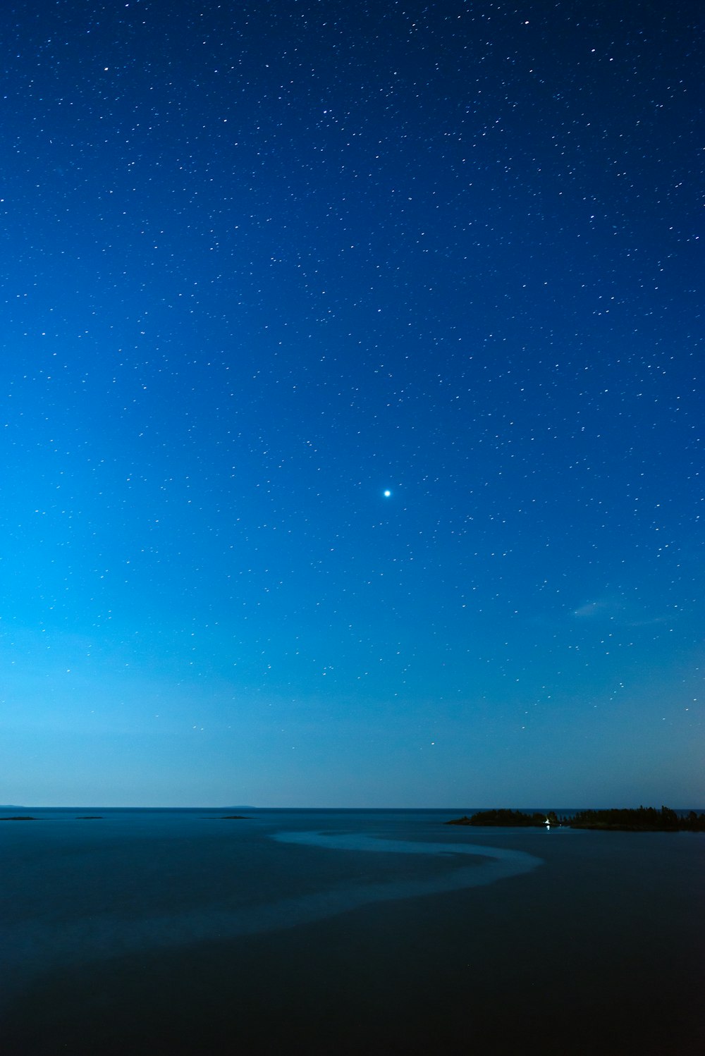 a body of water with a blue sky above it