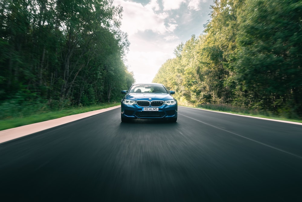 a blue car driving down a road