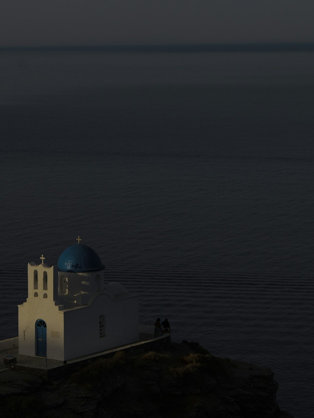 a white building on a cliff above water