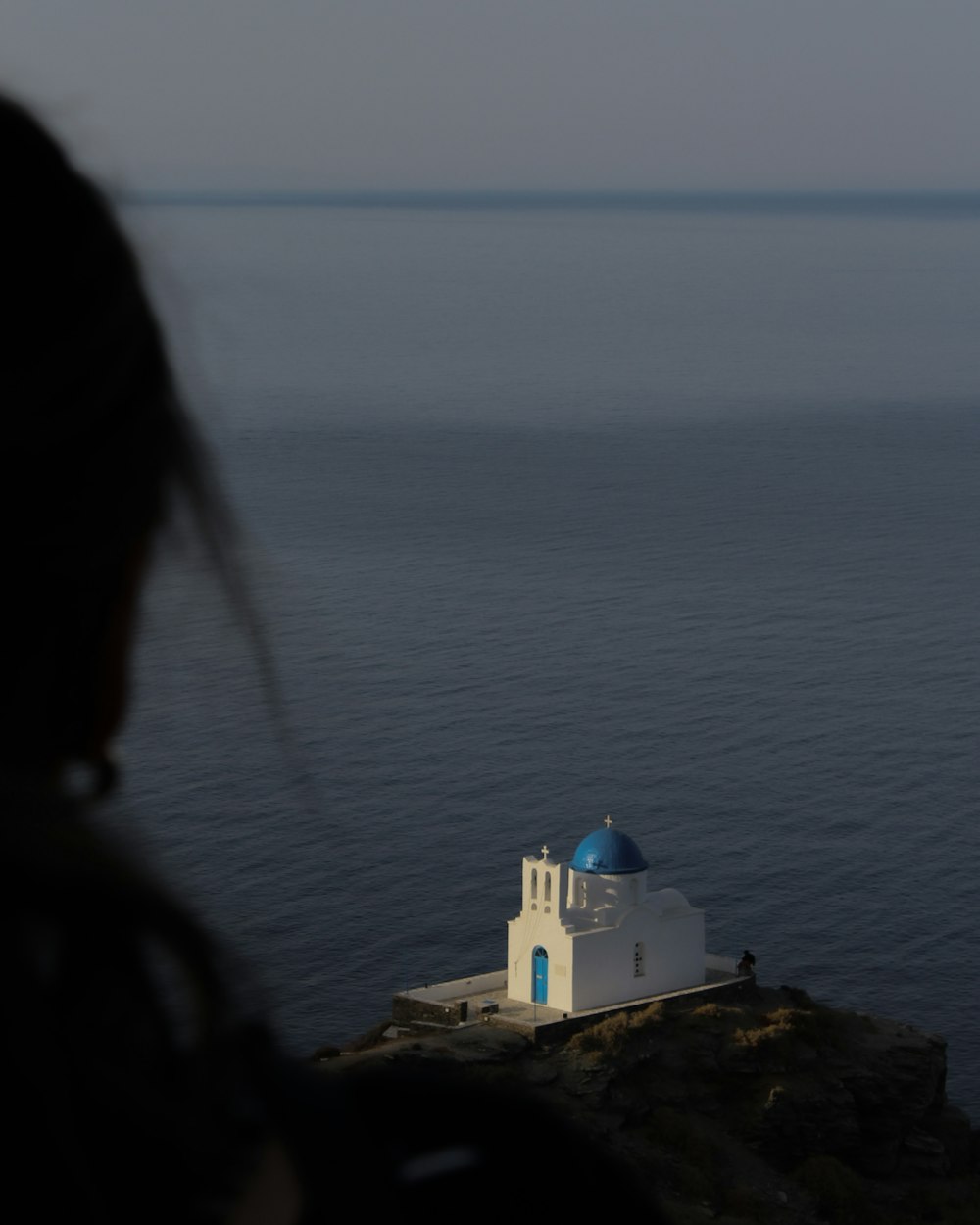 a white building on a cliff above the ocean