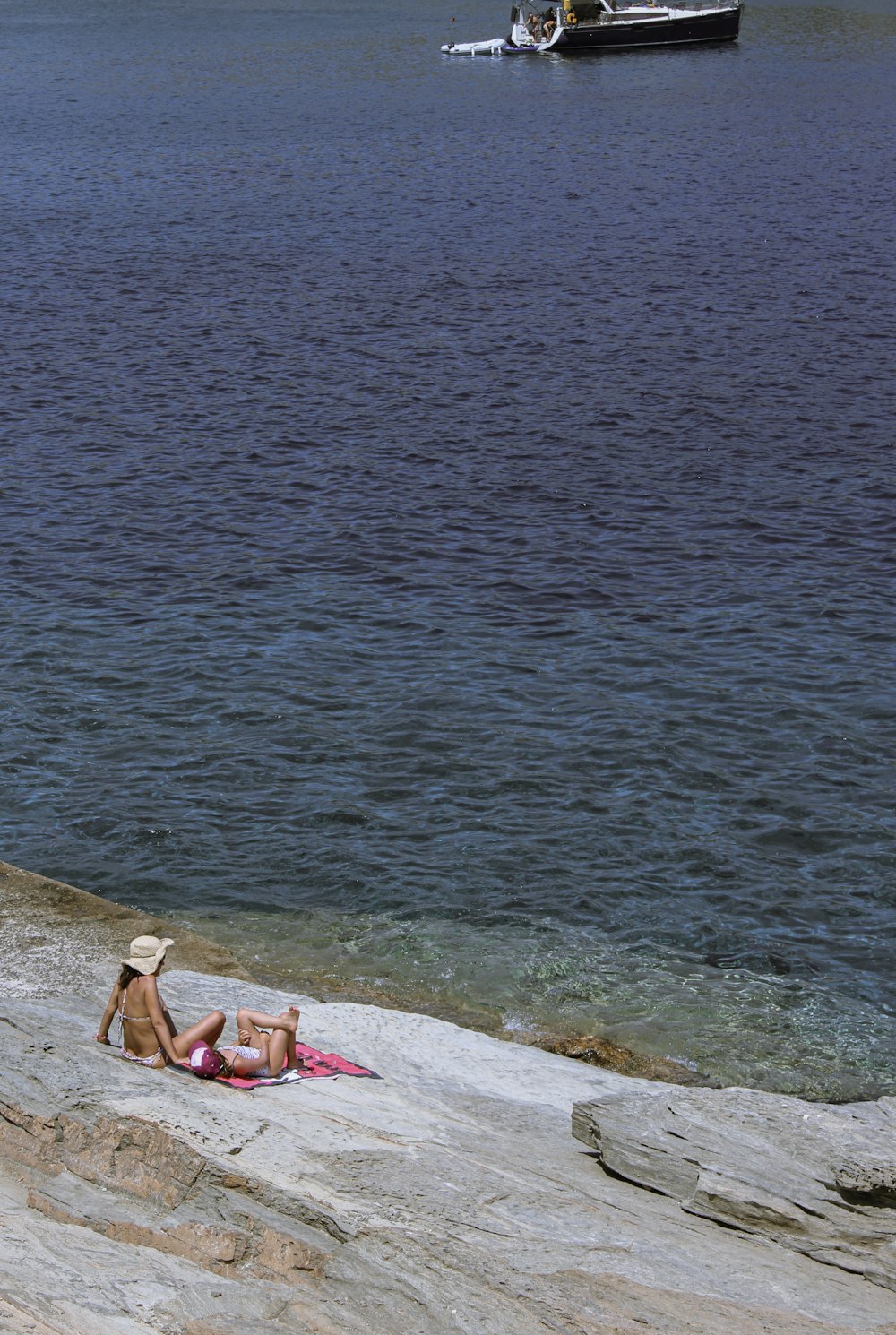 a person sitting on a rock by the water