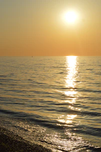 A joyful traveler looking at a golden sunset over a calm blue sea.