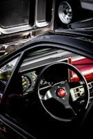 A stylish black leather steering wheel with red accents displayed in a modern workshop.