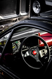 Close-up of a brushed titanium motorsport car dashboard with red accents on a deep black background.