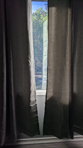 Sunlight streaming through spotless residential windows framed by maroon curtains.