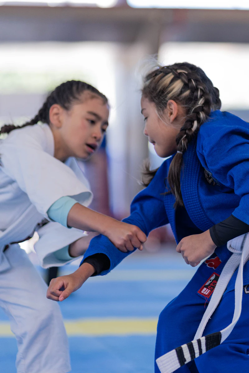 Children in white gi uniforms practicing martial arts in a dojo