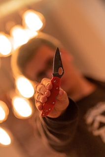 A close-up of a woman throwing a knife at a target with focus.
