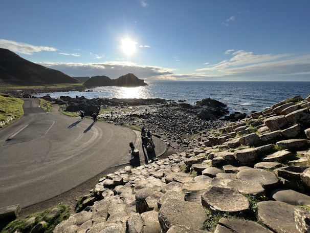 a road next to a body of water with rocks on the side