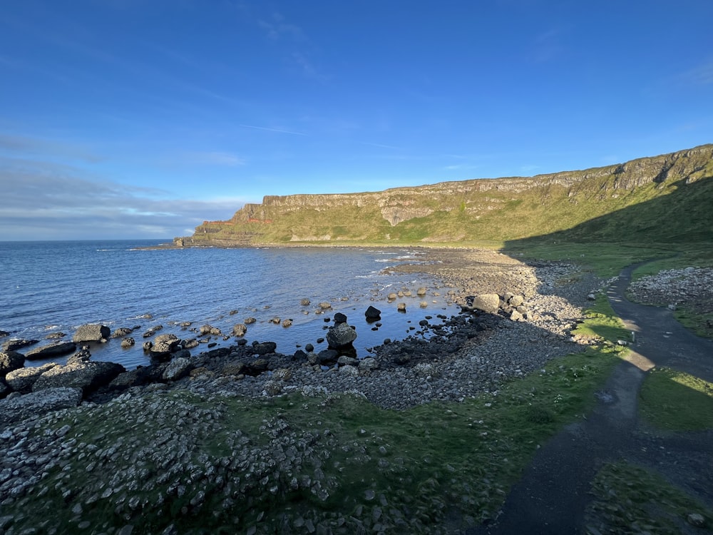 a rocky beach with a body of water and a hill with a hill in the background