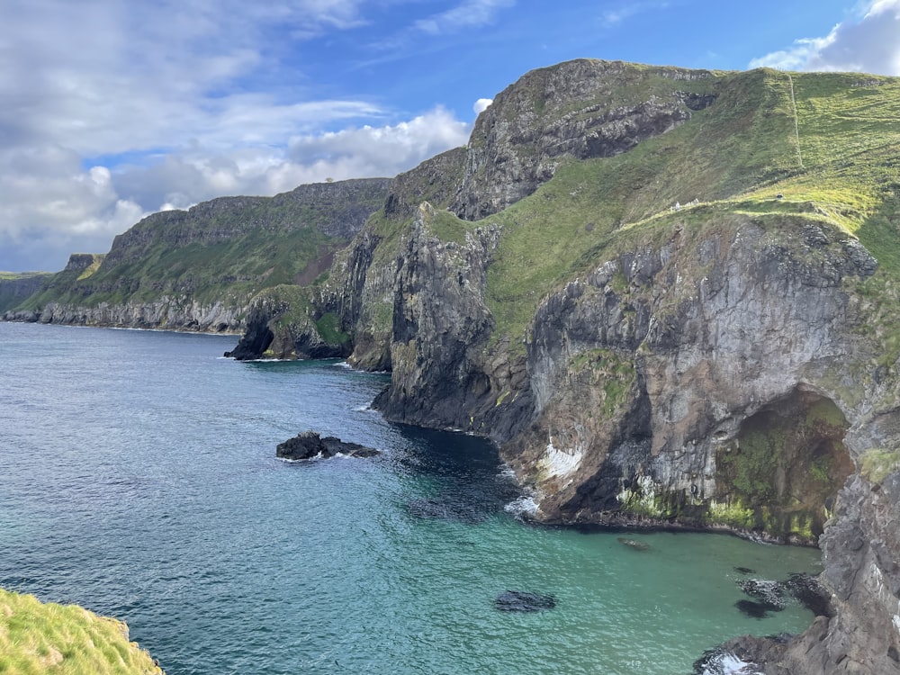 a rocky cliff next to a body of water