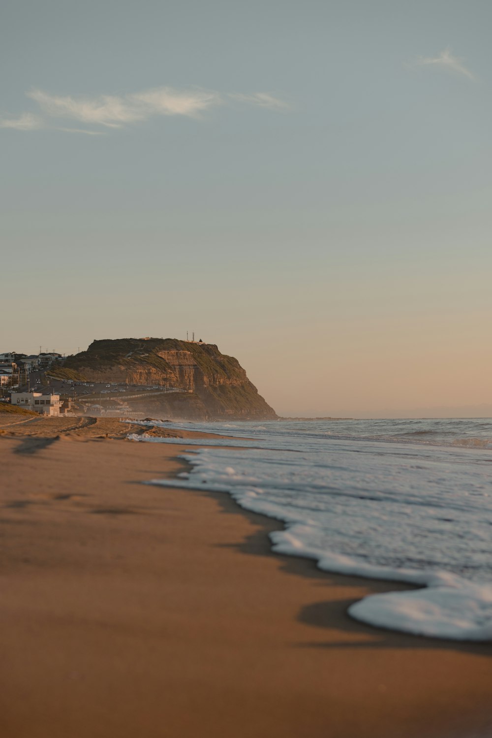 a beach with waves and a hill in the background