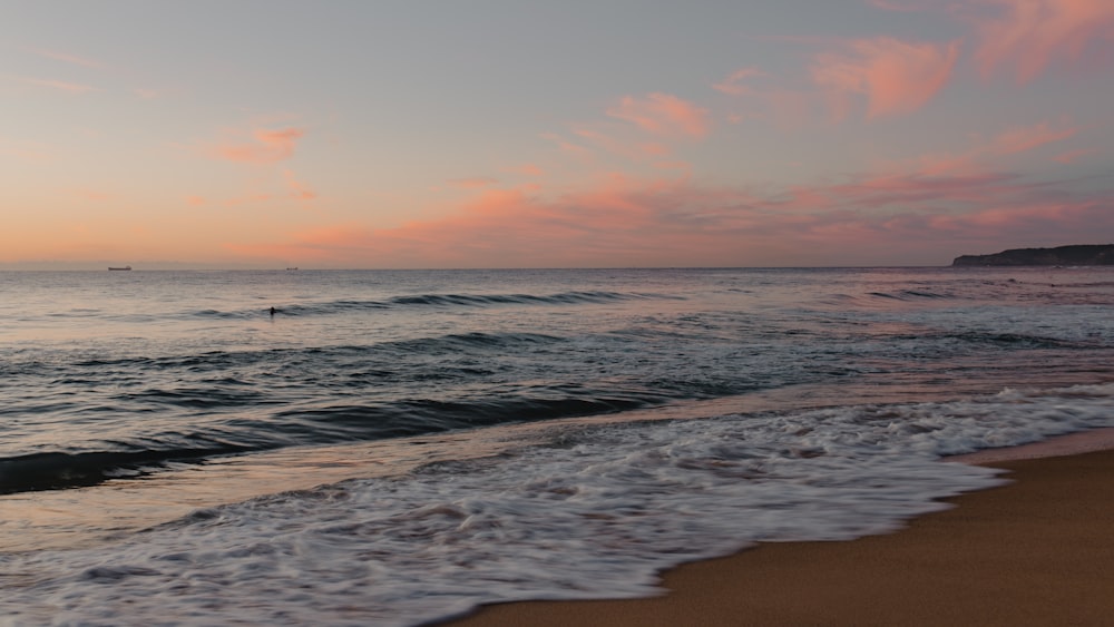 a beach with waves and a sunset