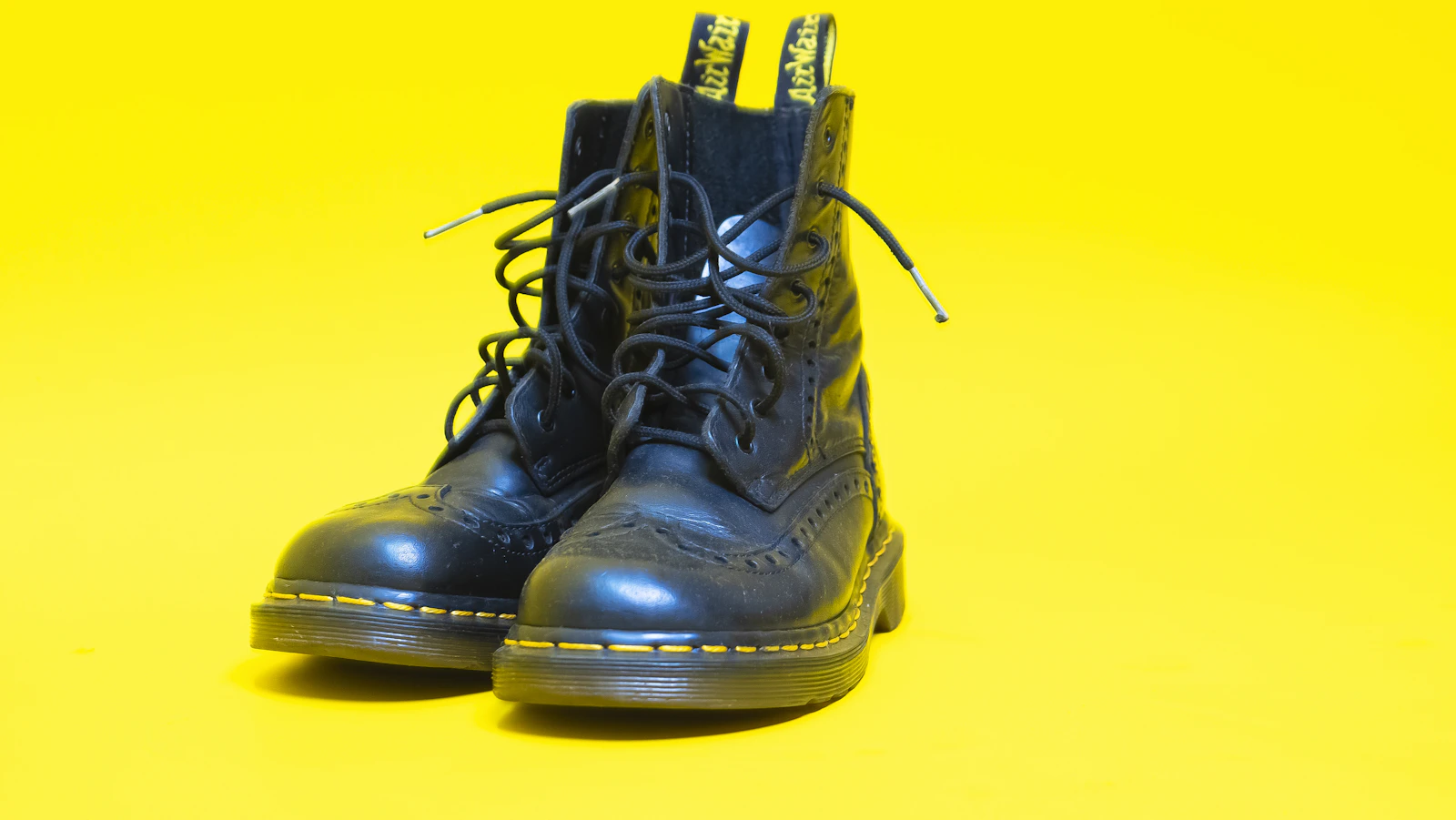 Black Dr. Martens 1460 boots on yellow