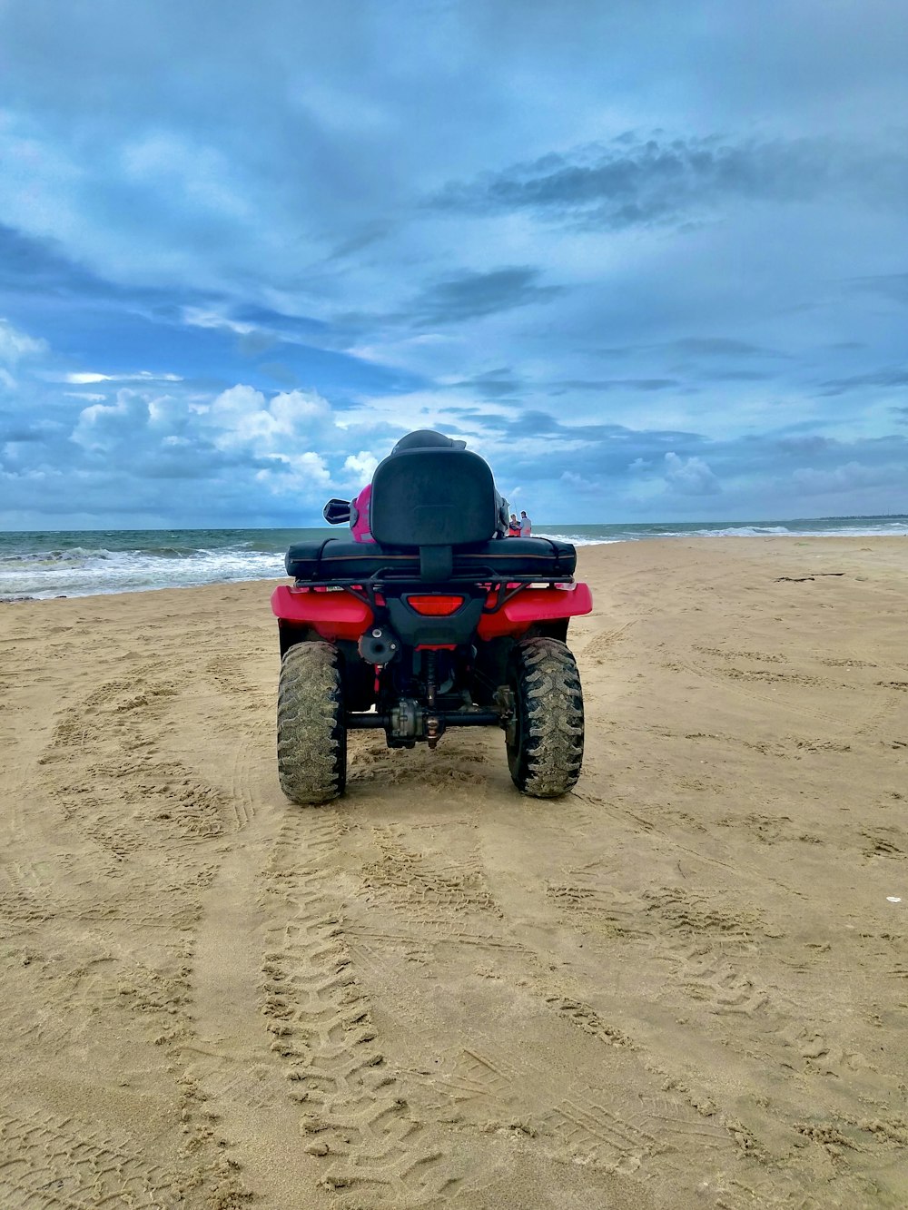 um veículo vermelho e preto em uma praia de areia