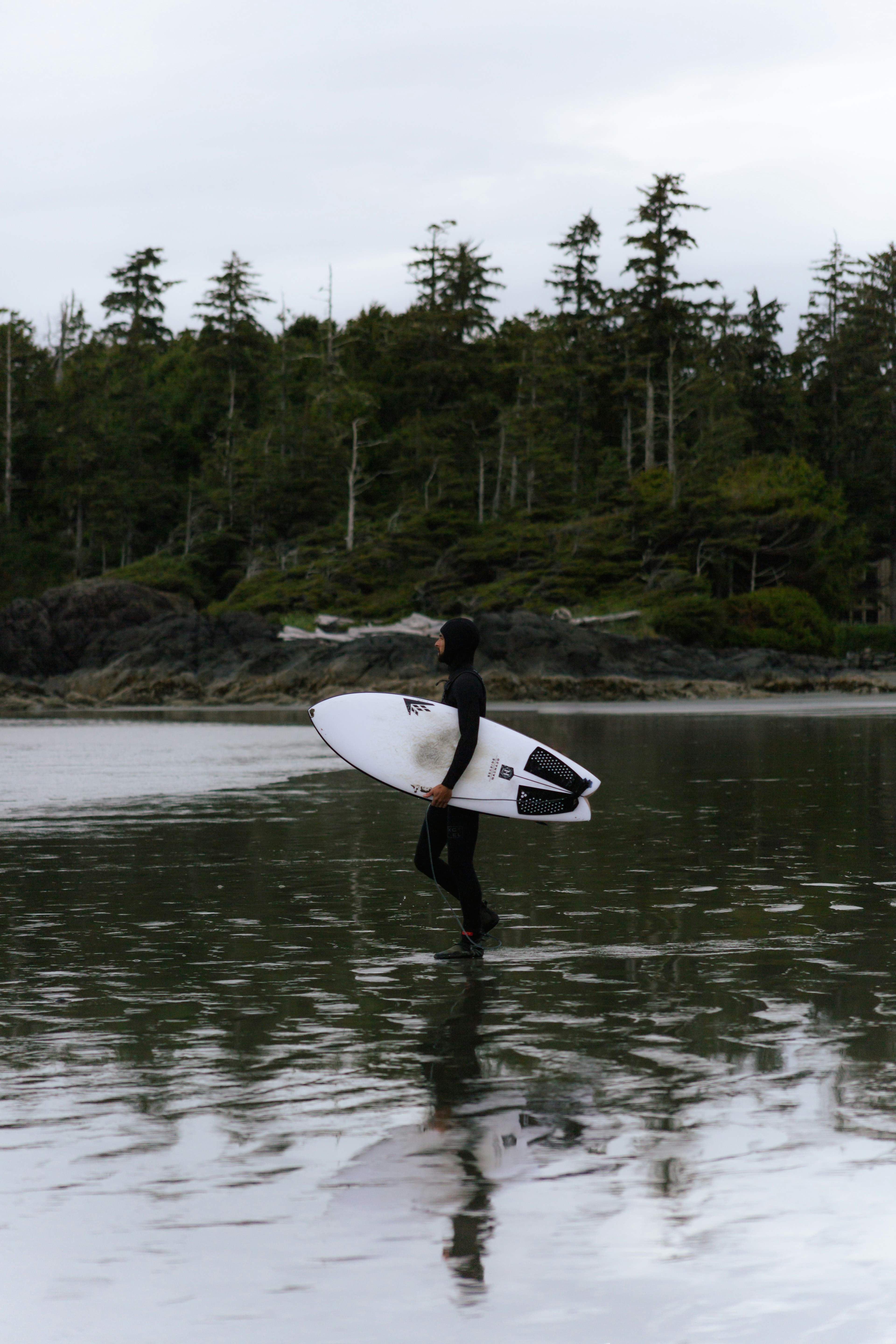 Un hombre cargando una tabla de surf en el agua