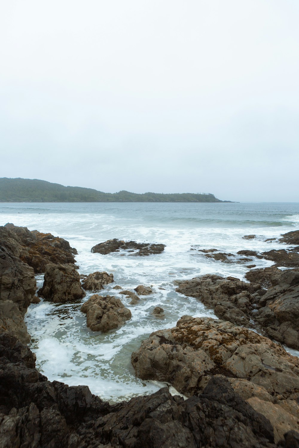 a rocky beach with a body of water in the background