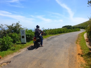 A happy tourist wearing a helmet, riding a motorbike along a scenic coastal road in Bali.