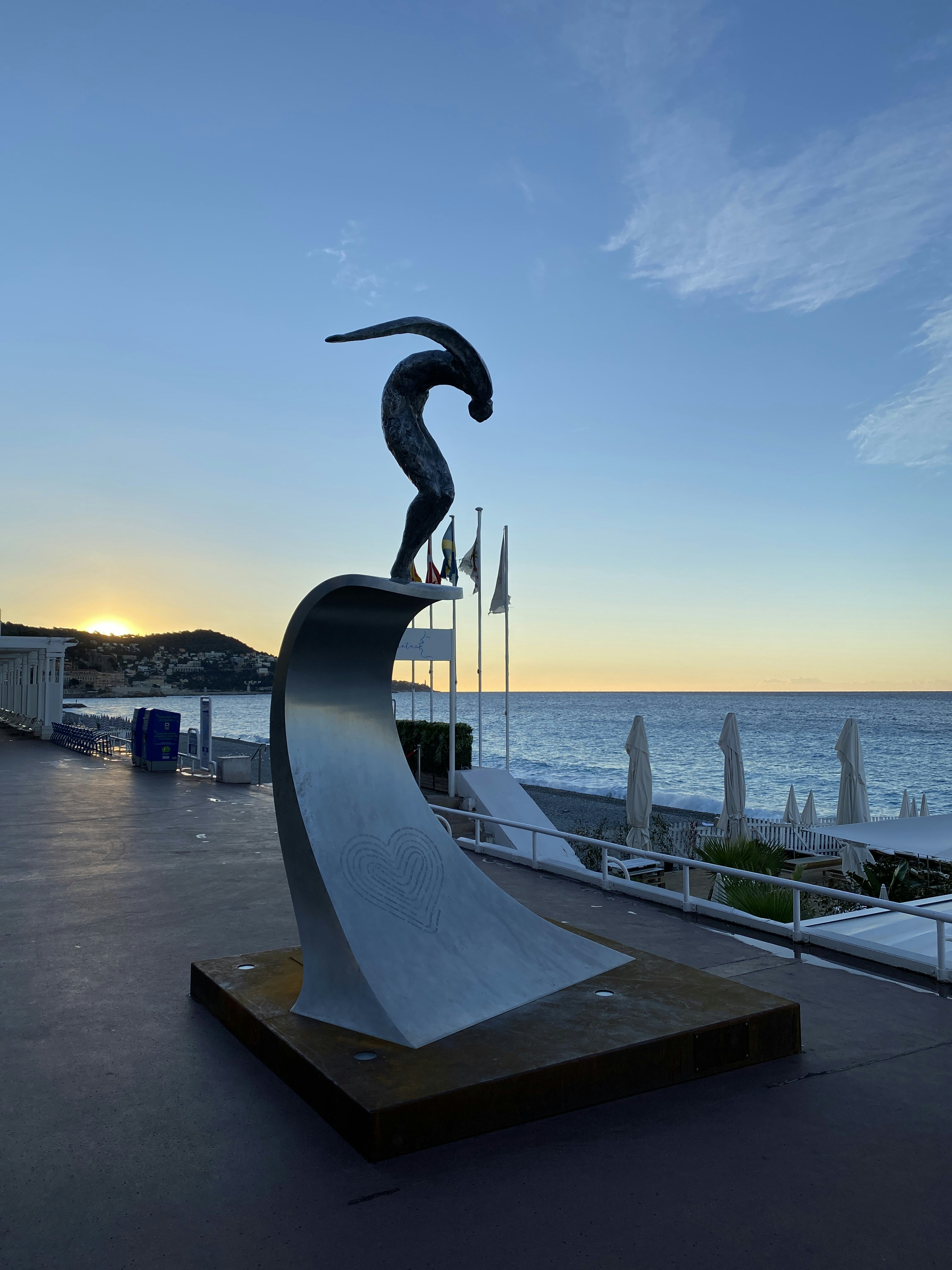 a statue of a person holding a torch on a platform by the water