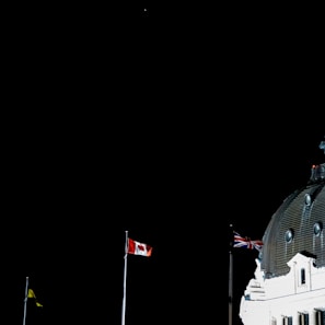 An image of the embassy building illuminated at night with the Canadian flag prominently displayed.