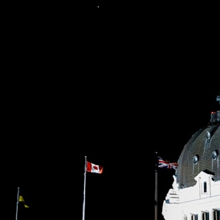 An image of the embassy building illuminated at night with the Canadian flag prominently displayed.